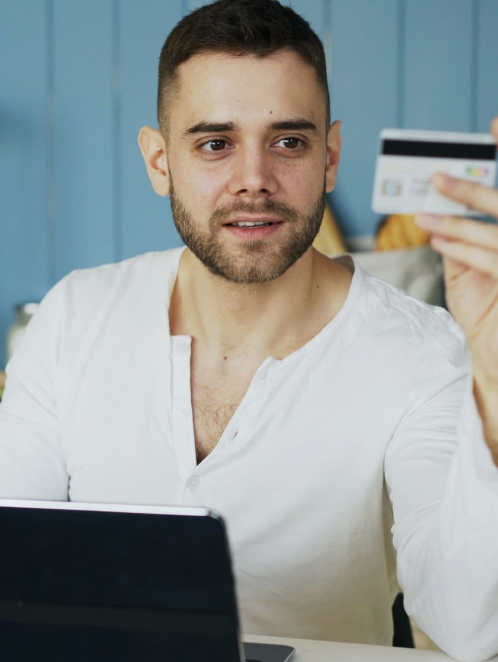 A customer holding up their payment card while reviewing a refund case on a laptop